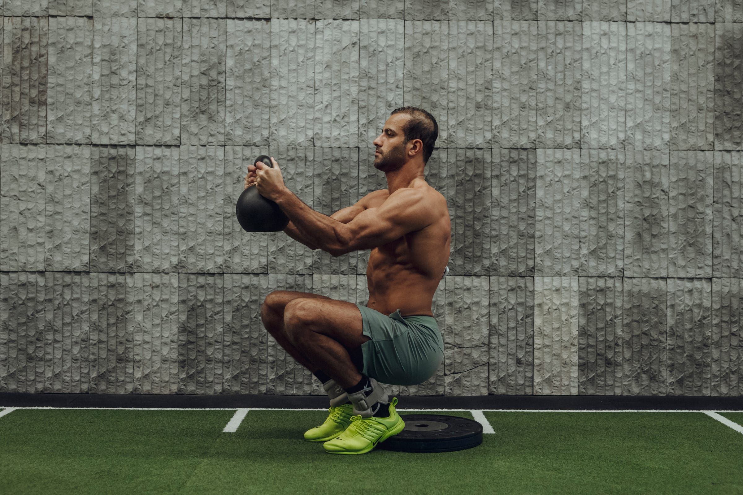 Mohamed Sultan holding a kettlebell at the bottom of a deep squat